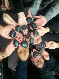 hands in a circle - each hand has a rock with an empowering word on it